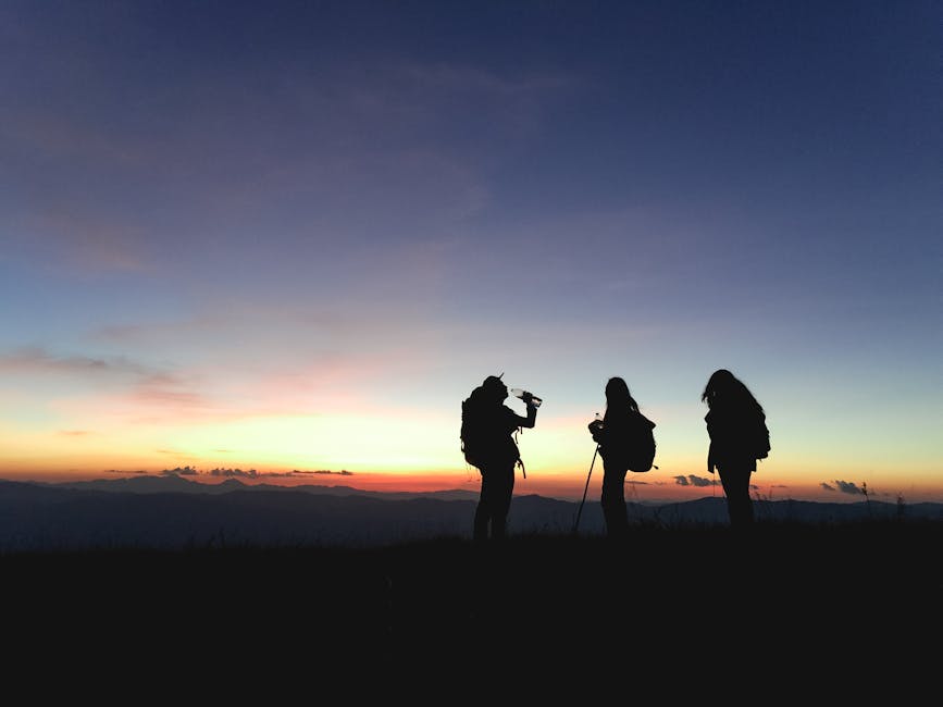 Group of hikers silhouetted against a vibrant sunset, enjoying an adventurous outdoor trek.